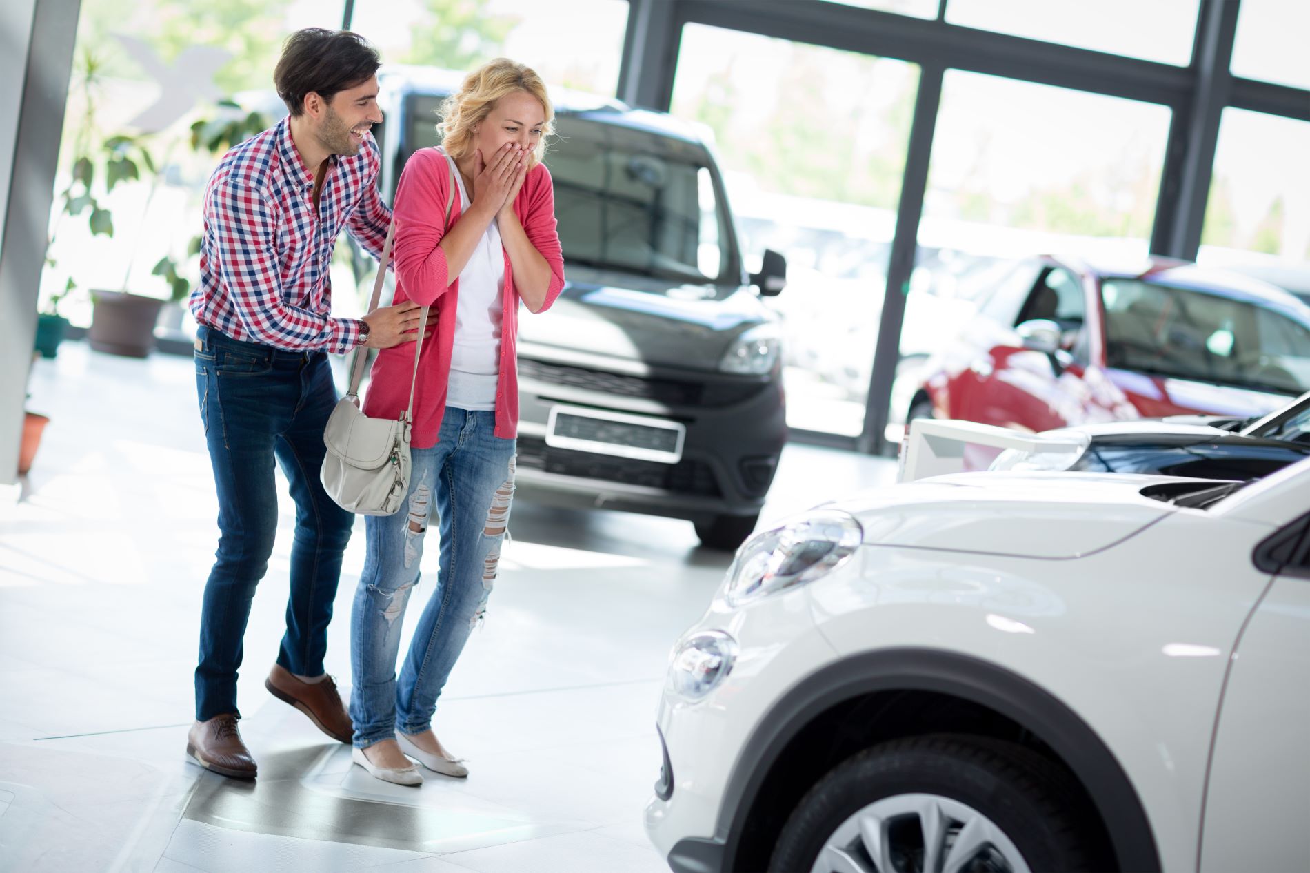 Couple at a car dealership celebrating a new car lease, replacing her current car lease 